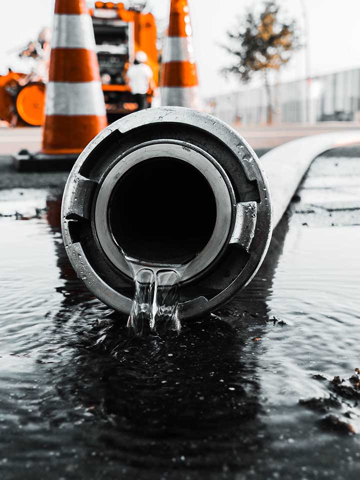 A selective closeup shot of a gray pipe with water coming out its hole